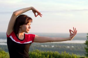 Woman doing tai chi on top of a mountain.